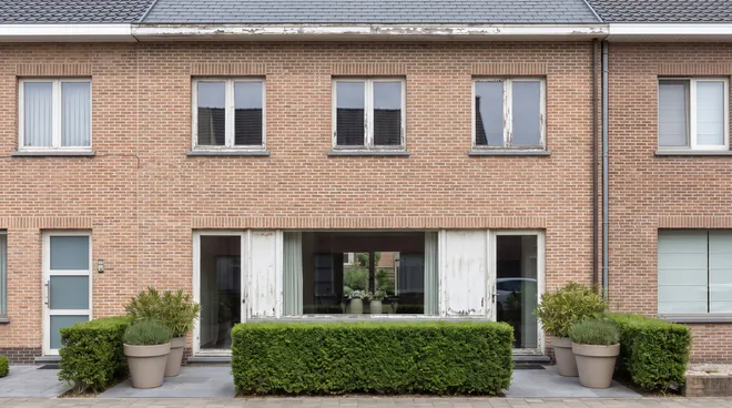 BEFORE photo — ageing white windows on a brick façade