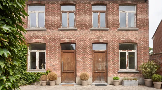 Foto VOOR — oude afgebladderde houten ramen op bakstenen gevel
