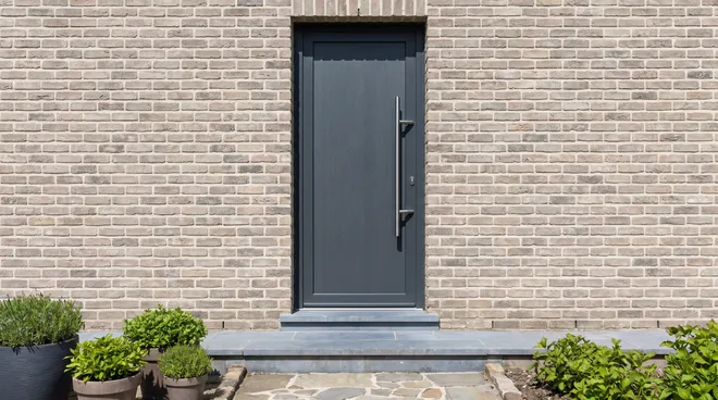 AFTER photo — solid anthracite RC2 aluminium door, stainless pull bar
